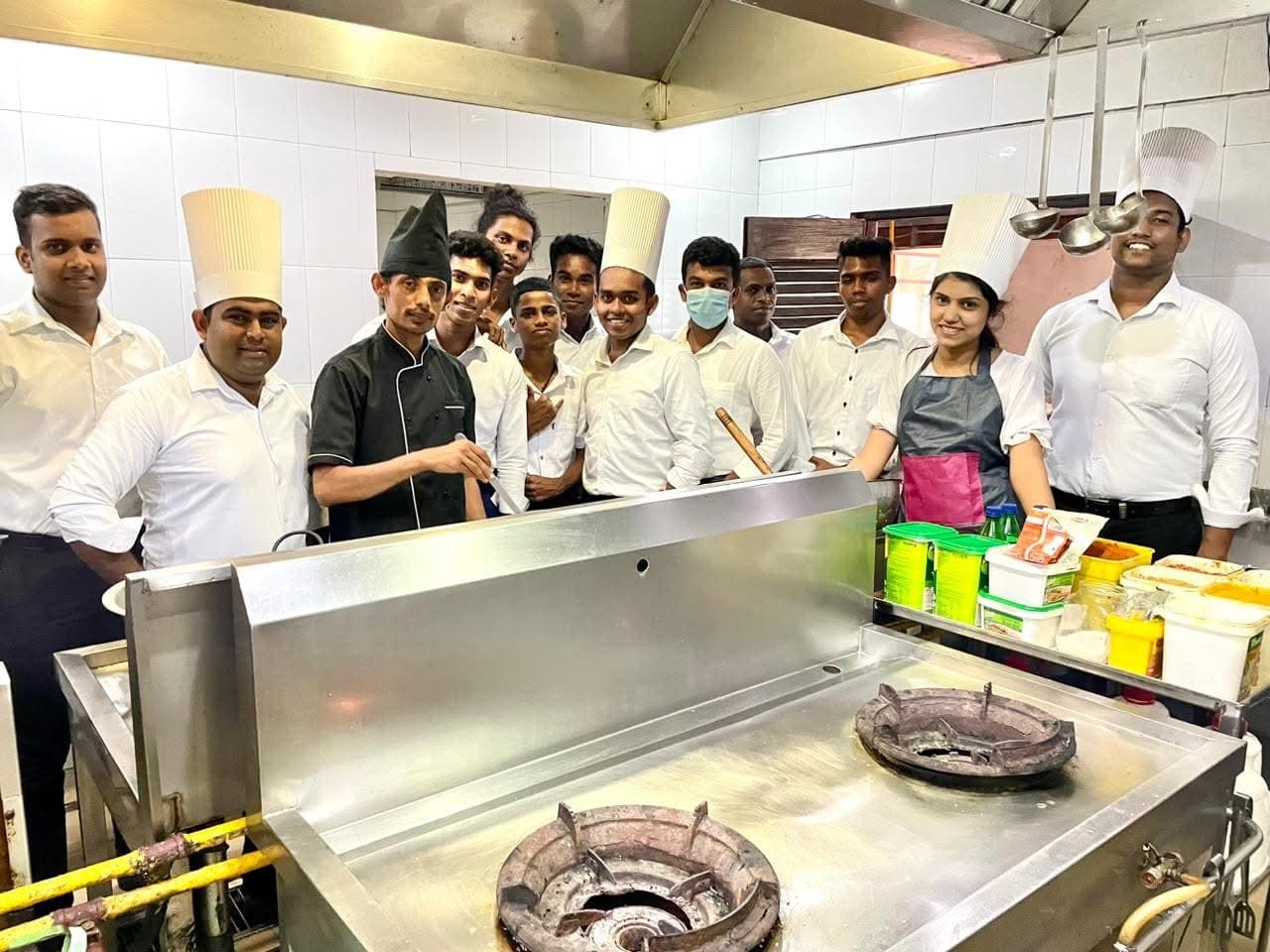 Carolina Academy trainers and hospitality students in chef whites in the practical training kitchen